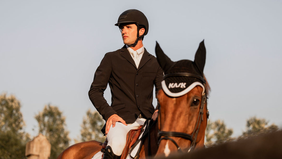 Rider in a dark show jacket on a bay horse at golden hour