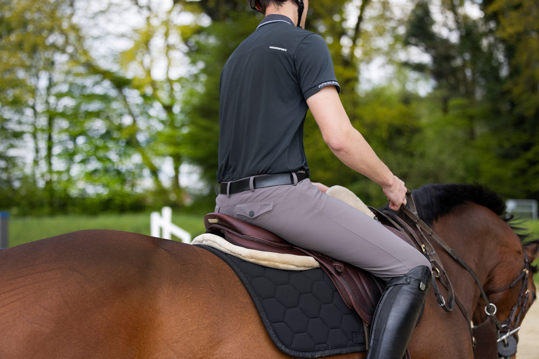 Rider seated in the saddle with boots in the stirrups on a bay horse